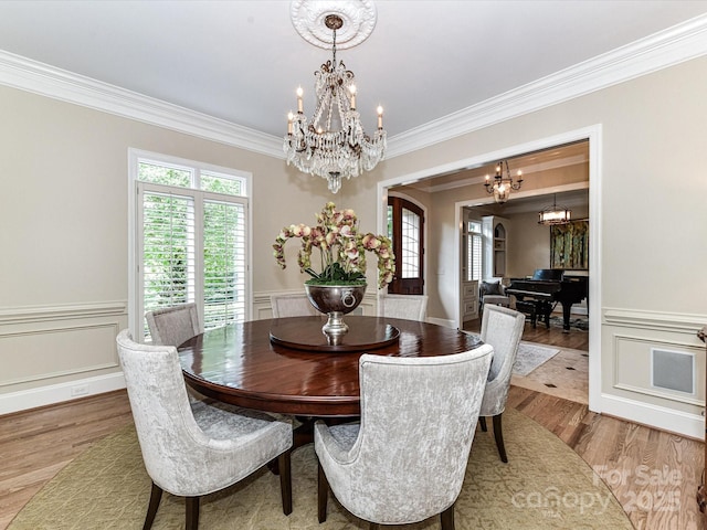 dining area with a chandelier, ornamental molding, wood finished floors, and a wealth of natural light