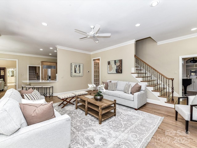 living room featuring ceiling fan, stairway, ornamental molding, recessed lighting, and light wood-style flooring