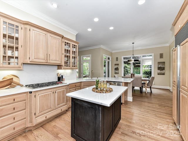 kitchen with a peninsula, light brown cabinetry, a sink, light wood finished floors, and stainless steel gas stovetop