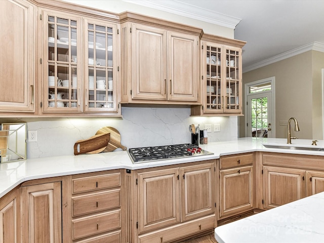 kitchen with decorative backsplash, stainless steel gas cooktop, a sink, glass insert cabinets, and ornamental molding