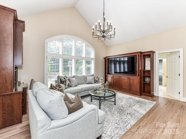 living area featuring high vaulted ceiling, a chandelier, and light wood-style floors