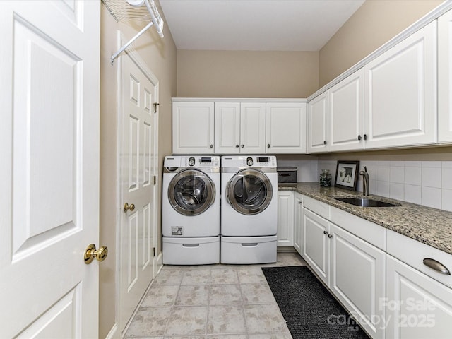 clothes washing area featuring a sink, separate washer and dryer, and cabinet space