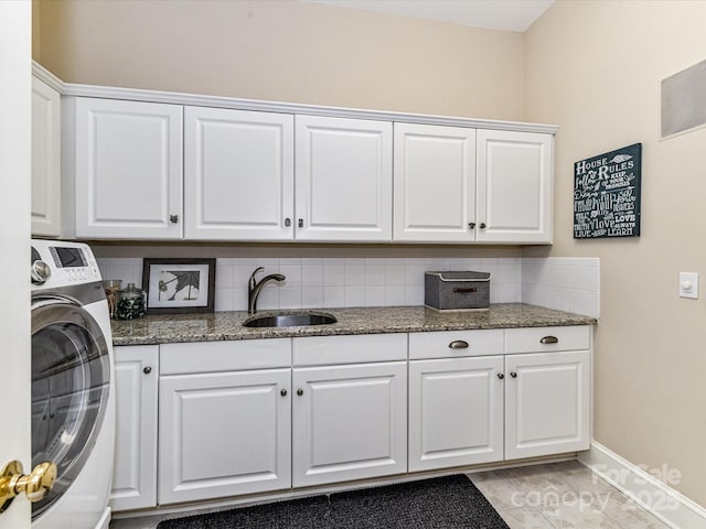 laundry area with baseboards, a sink, washer / dryer, and cabinet space
