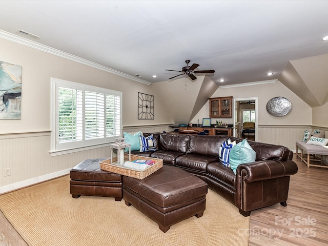 living room with a wainscoted wall, ceiling fan, wood finished floors, and visible vents