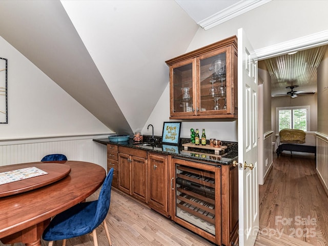 bar with wine cooler, light wood-style floors, vaulted ceiling, and a sink