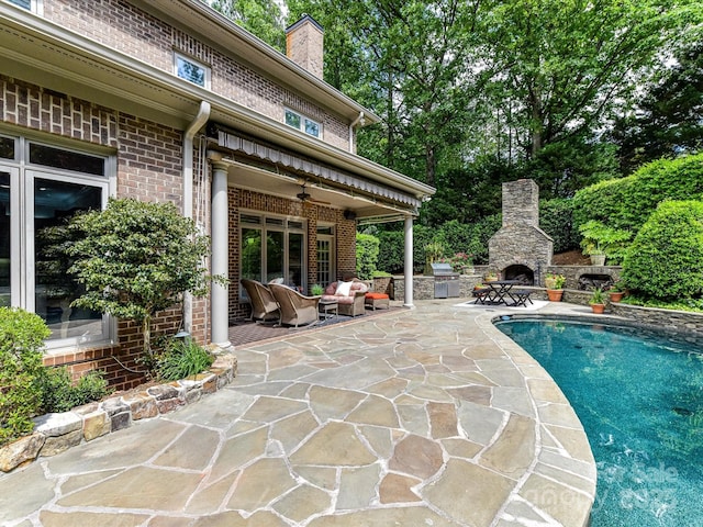 outdoor pool featuring a patio, a ceiling fan, and an outdoor living space with a fireplace
