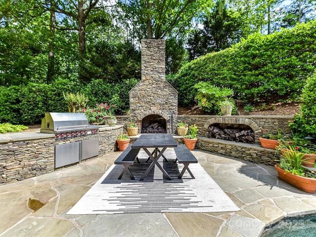 view of patio with area for grilling, an outdoor stone fireplace, and outdoor dining space