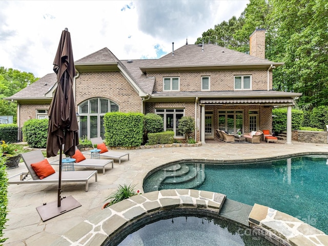 back of property featuring brick siding, a chimney, and a patio