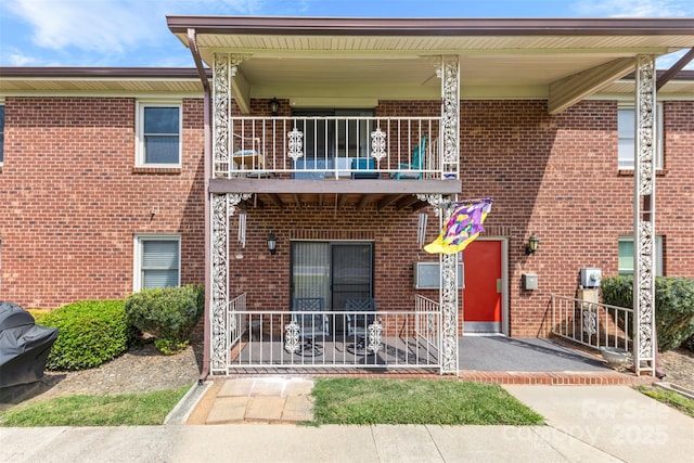view of front facade featuring brick siding and a balcony