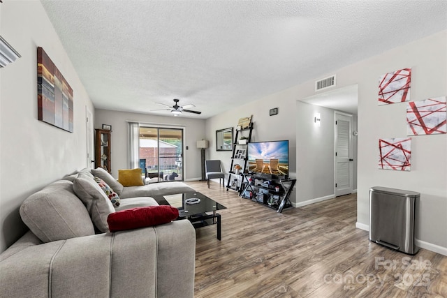 living room with a textured ceiling, ceiling fan, visible vents, and light wood finished floors