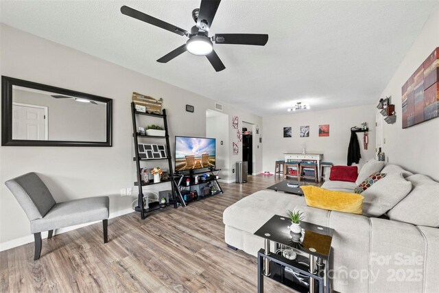 living room featuring baseboards, ceiling fan, wood finished floors, and visible vents