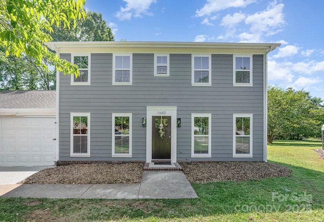 colonial-style house featuring an attached garage, driveway, and a front lawn
