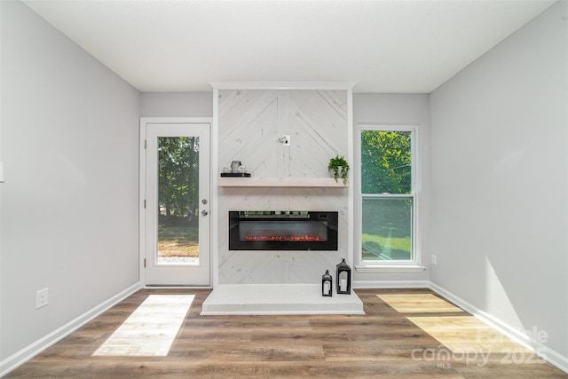 unfurnished living room with baseboards, wood finished floors, and a fireplace