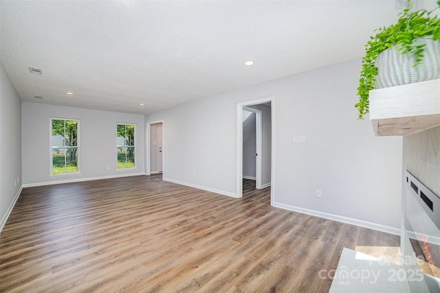 unfurnished living room featuring baseboards, recessed lighting, and wood finished floors