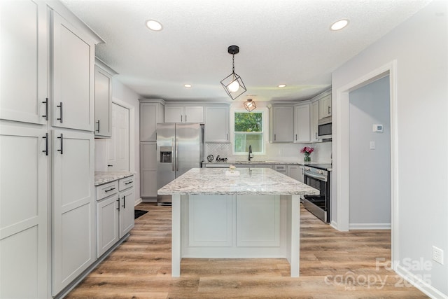 kitchen featuring a sink, appliances with stainless steel finishes, gray cabinetry, and tasteful backsplash