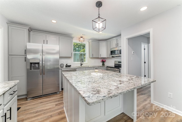 kitchen with a sink, gray cabinets, appliances with stainless steel finishes, and light wood finished floors