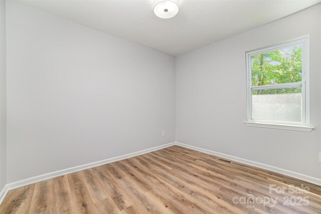 empty room with baseboards, visible vents, and light wood-style floors