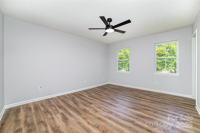 spare room with a ceiling fan, baseboards, visible vents, and wood finished floors