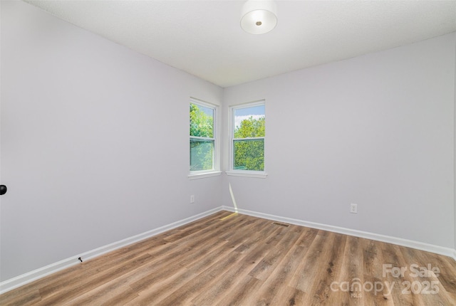 spare room with baseboards, light wood finished floors, and visible vents