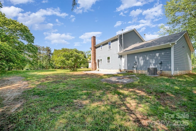 rear view of property with a lawn, central air condition unit, and a chimney
