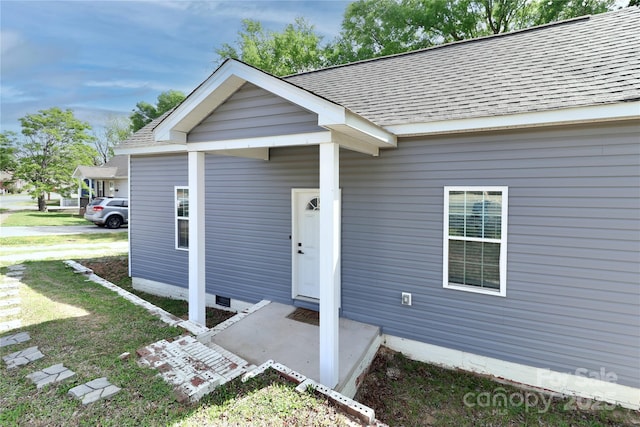 view of front of property with roof with shingles, a front yard, and crawl space