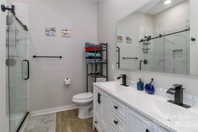 full bath with a shower stall, wood finished floors, toilet, and double vanity