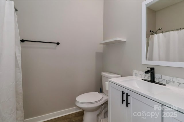 bathroom with wood finished floors, toilet, vanity, and baseboards