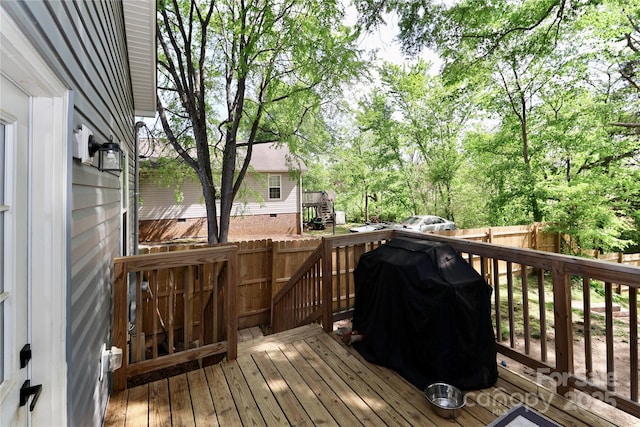 wooden terrace with a fenced backyard and area for grilling