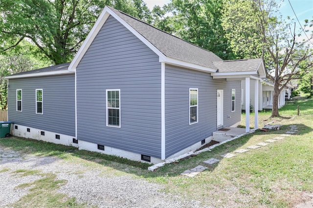 view of side of home with crawl space, a shingled roof, and a lawn