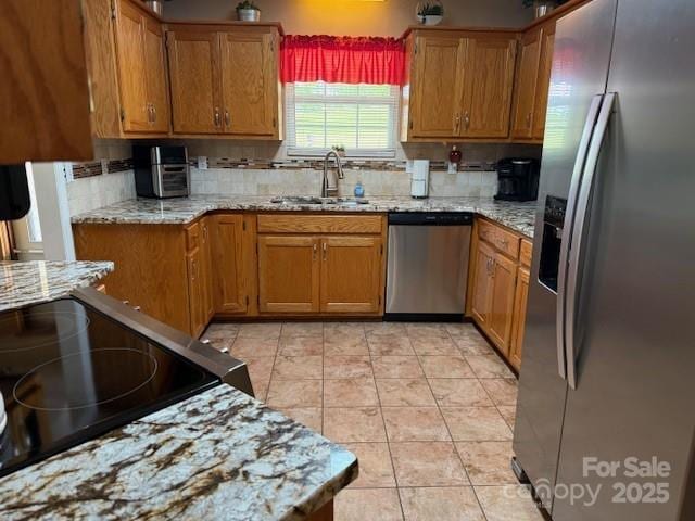 kitchen with brown cabinets, tasteful backsplash, stainless steel appliances, and a sink