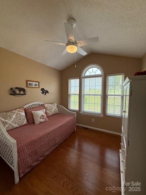 bedroom featuring lofted ceiling, baseboards, wood finished floors, and a textured ceiling