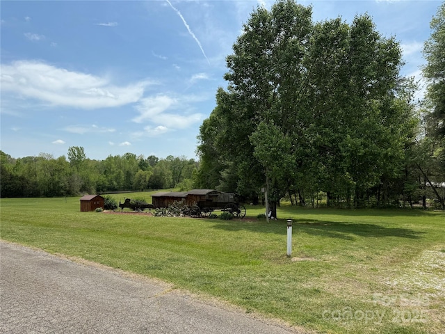 view of home's community with a yard, an outbuilding, and a wooded view