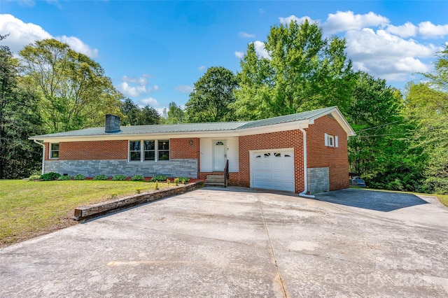 ranch-style house featuring a chimney, a garage, driveway, a front yard, and metal roof