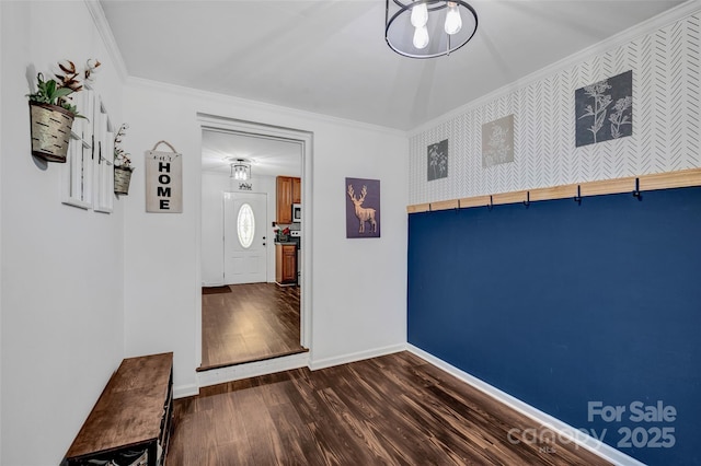 foyer featuring dark wood-type flooring, wallpapered walls, baseboards, and ornamental molding