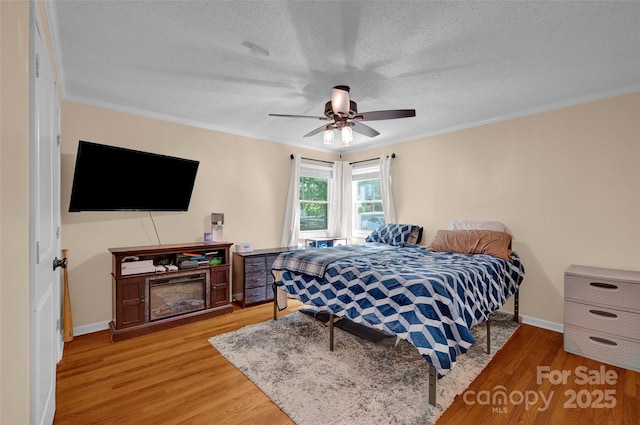 bedroom featuring crown molding, a textured ceiling, and light wood-type flooring