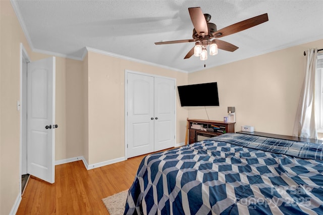 bedroom with light wood finished floors, a closet, crown molding, baseboards, and a textured ceiling