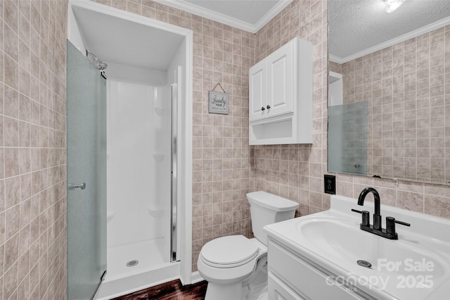 bathroom featuring a textured ceiling, toilet, tile walls, a stall shower, and ornamental molding