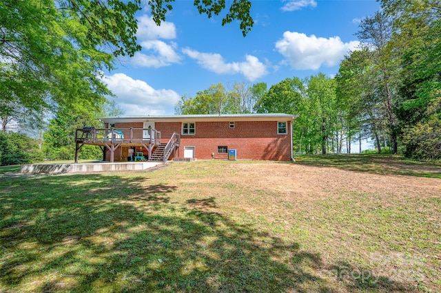 back of house with stairway, brick siding, a yard, and a deck