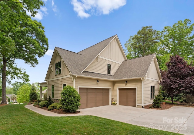 view of home's exterior featuring roof with shingles, driveway, an attached garage, board and batten siding, and a yard