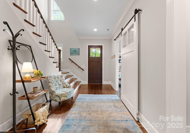 entryway featuring baseboards, a barn door, stairway, and dark wood finished floors