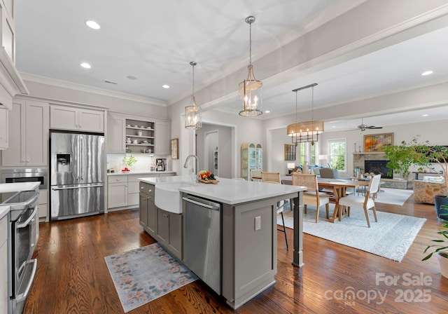 kitchen with stainless steel appliances, a sink, open floor plan, light countertops, and a fireplace