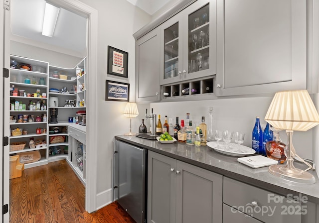 bar featuring a dry bar, stainless steel refrigerator, and dark wood-style floors