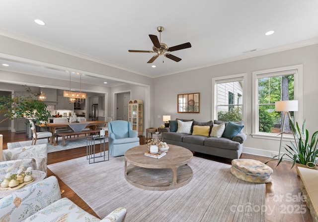 living area with wood finished floors, ceiling fan with notable chandelier, baseboards, visible vents, and recessed lighting