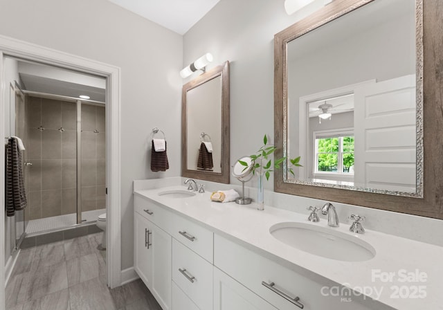 full bath featuring a sink, a shower stall, double vanity, and toilet