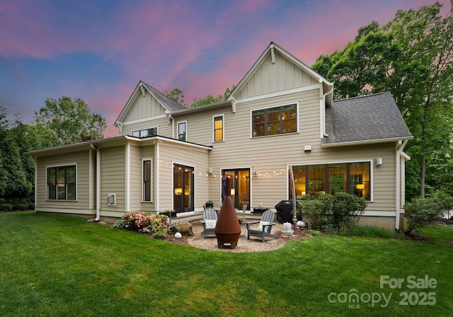 rear view of property featuring board and batten siding, a lawn, and a patio area