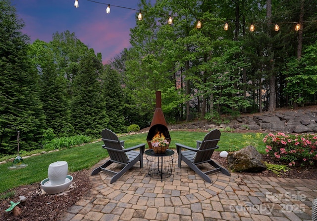 patio terrace at dusk featuring a fire pit and a yard