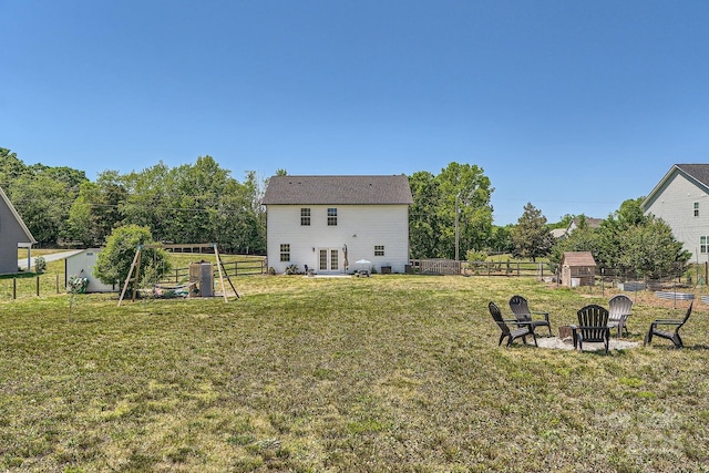 view of yard featuring an outdoor fire pit, fence, french doors, and a shed