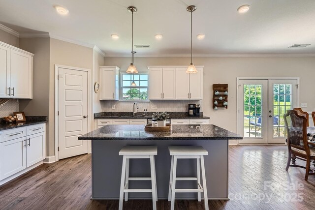 kitchen with a breakfast bar area, a kitchen island, backsplash, dark wood finished floors, and a sink