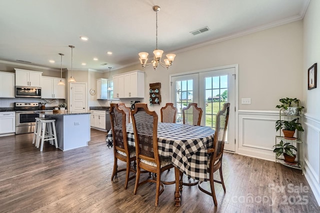 dining area featuring visible vents, ornamental molding, dark wood-type flooring, and a notable chandelier