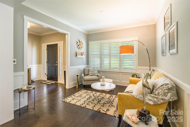 sitting room with a decorative wall, crown molding, a wainscoted wall, and wood finished floors